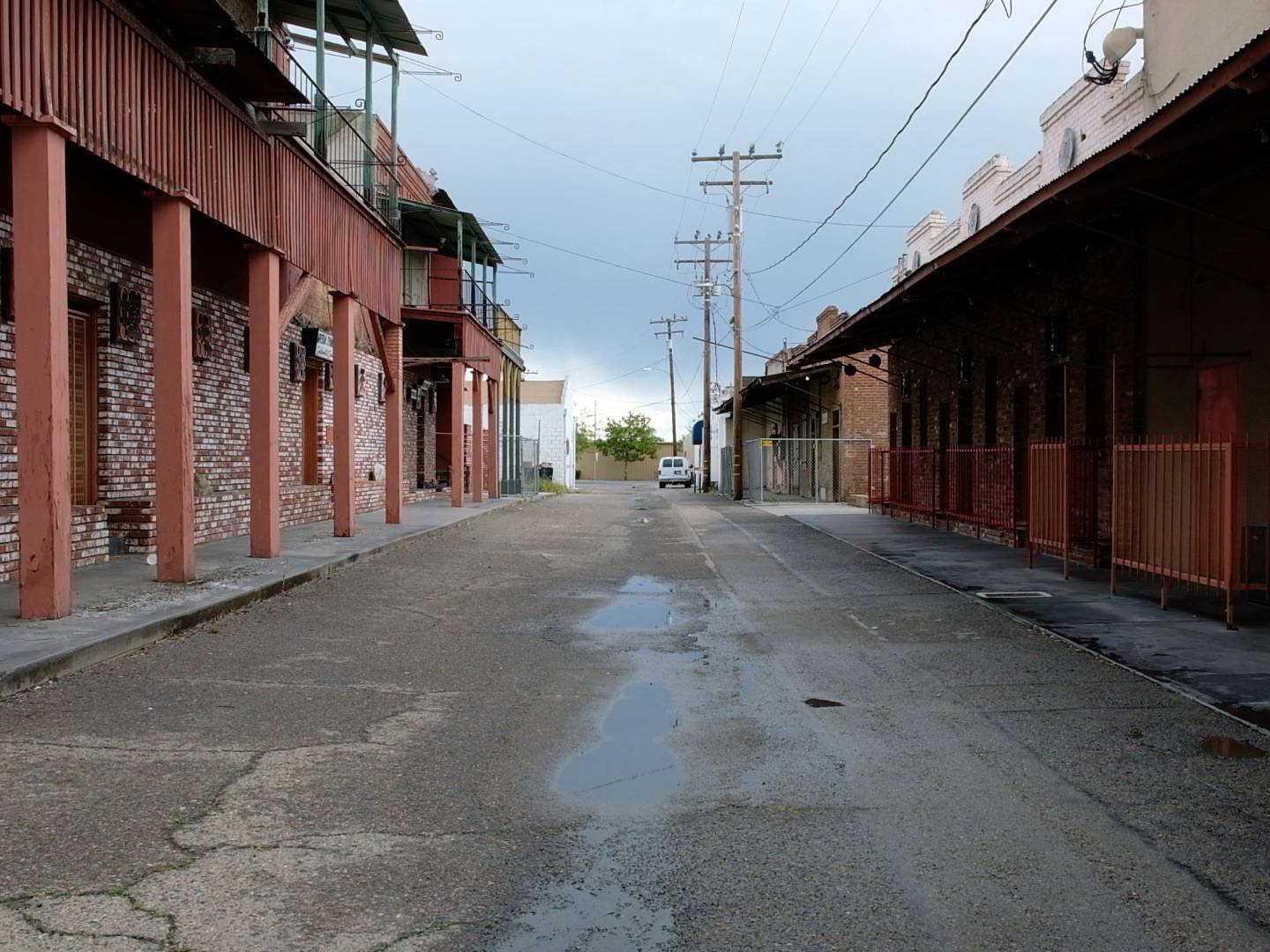 A photograph of a mostly empty alleyway between two rows of reddish-brown buildings