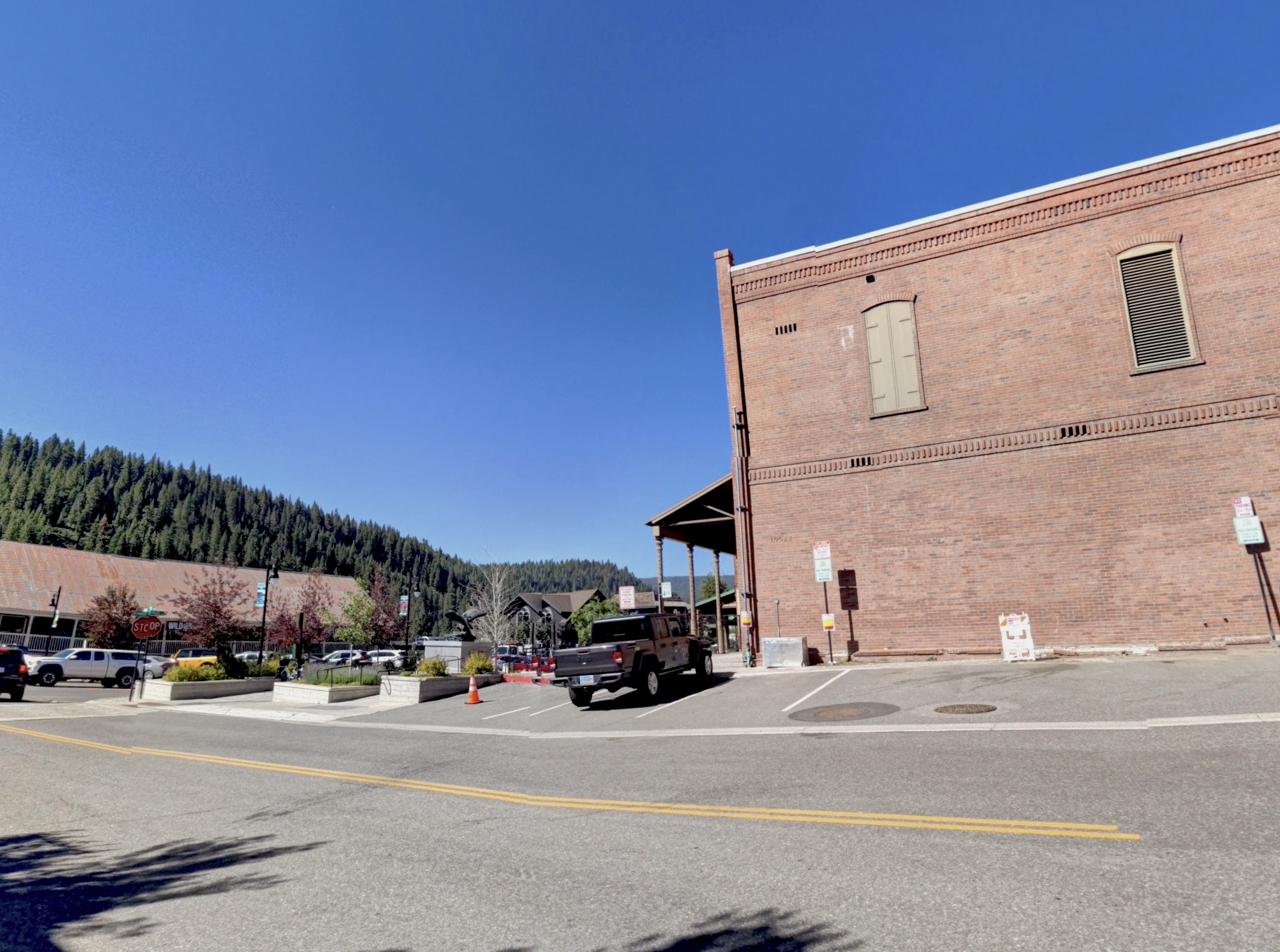 A photograph of a street in front of a parking lot and a brick building